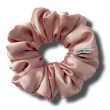 Pink scrunchie with a visible brand label on a white background