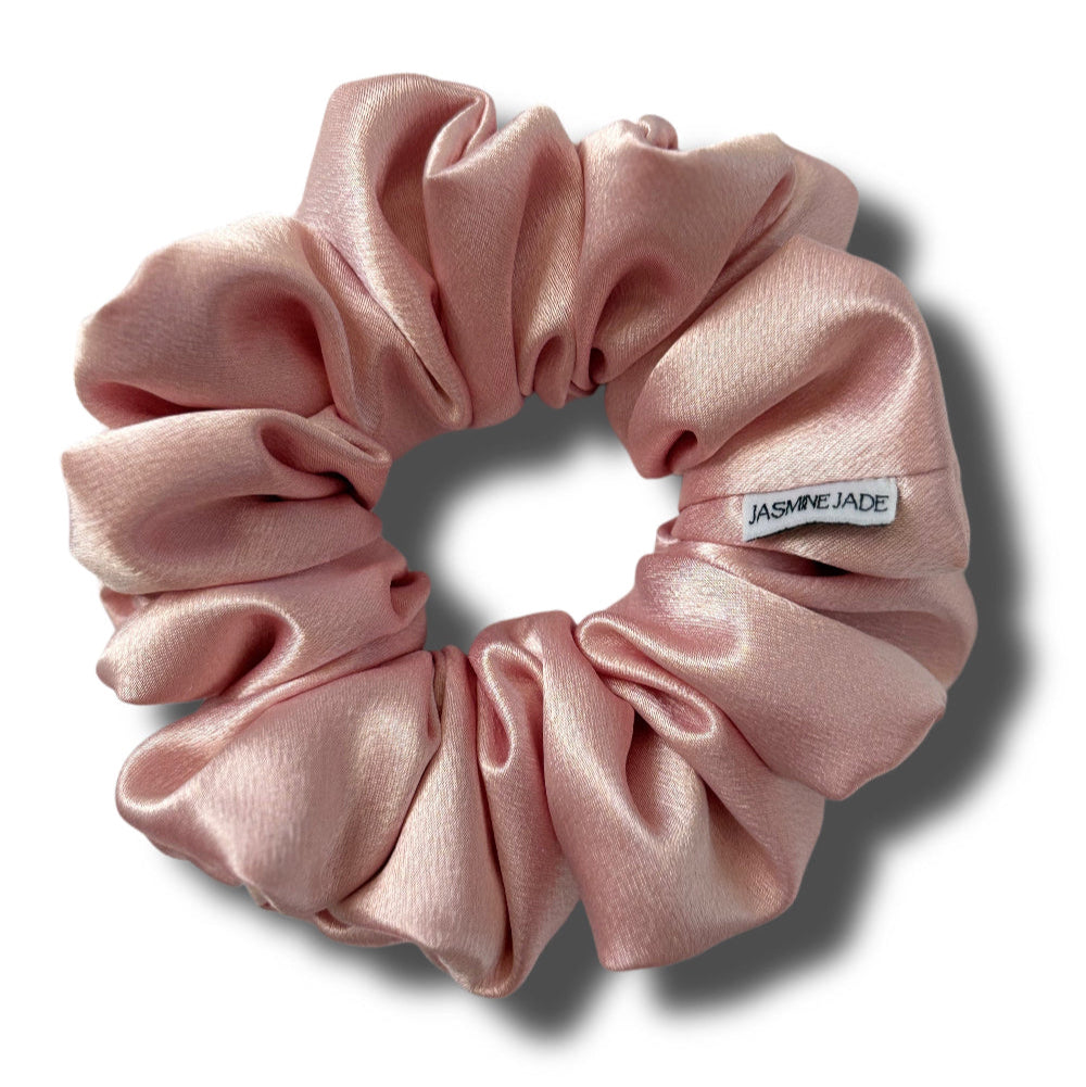 Pink scrunchie with a visible brand label on a white background