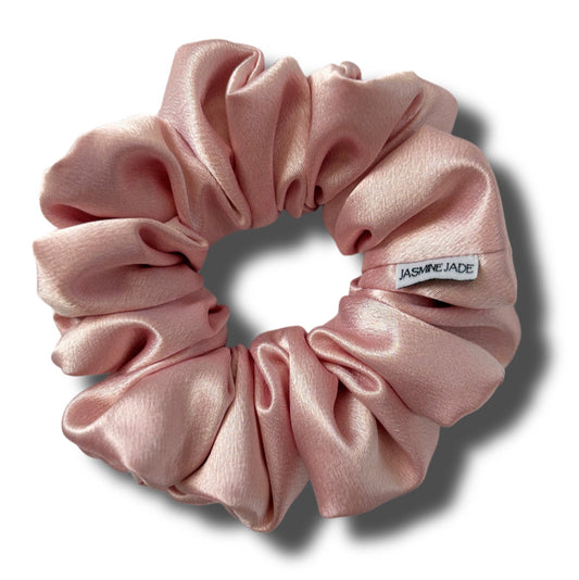 Pink scrunchie with a visible brand label on a white background