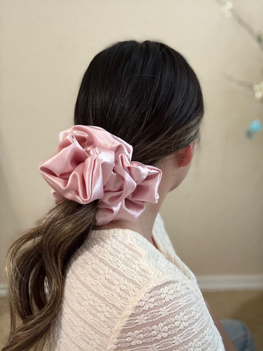 Person with pink scrunchie in hair against a neutral background
