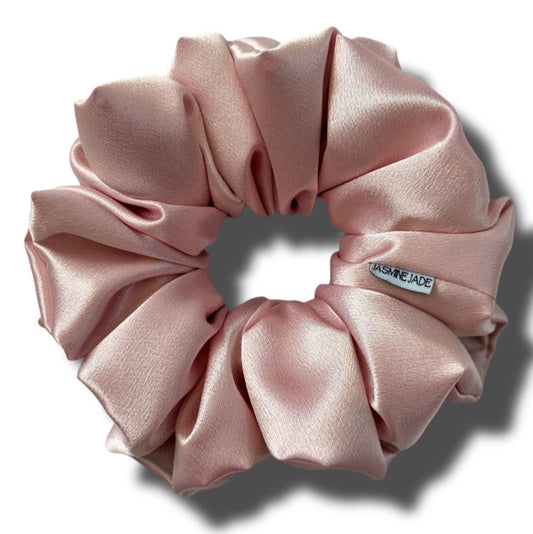 Pink scrunchie with a brand label on a white background
