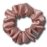 Pink satin scrunchie with a brand label on a white background