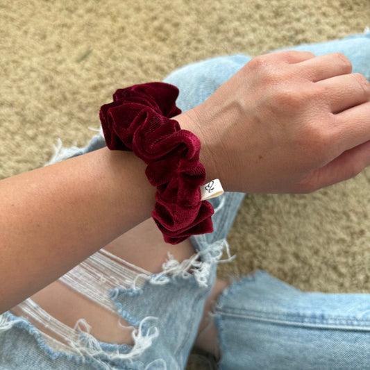 Red scrunchie on a wrist with a blurred background
