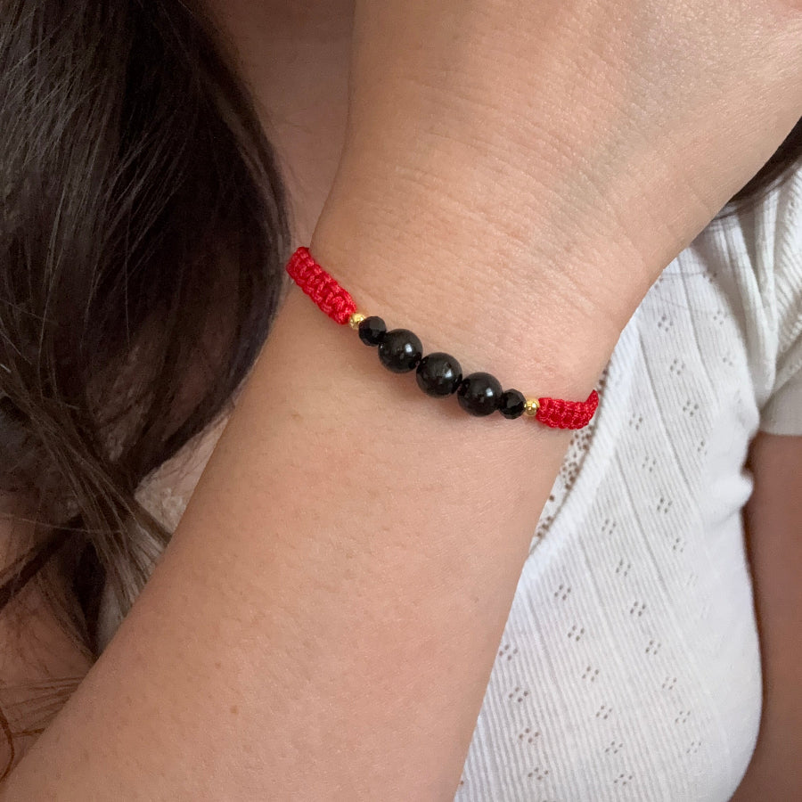 Close-up of a wrist wearing a red and black beaded bracelet.