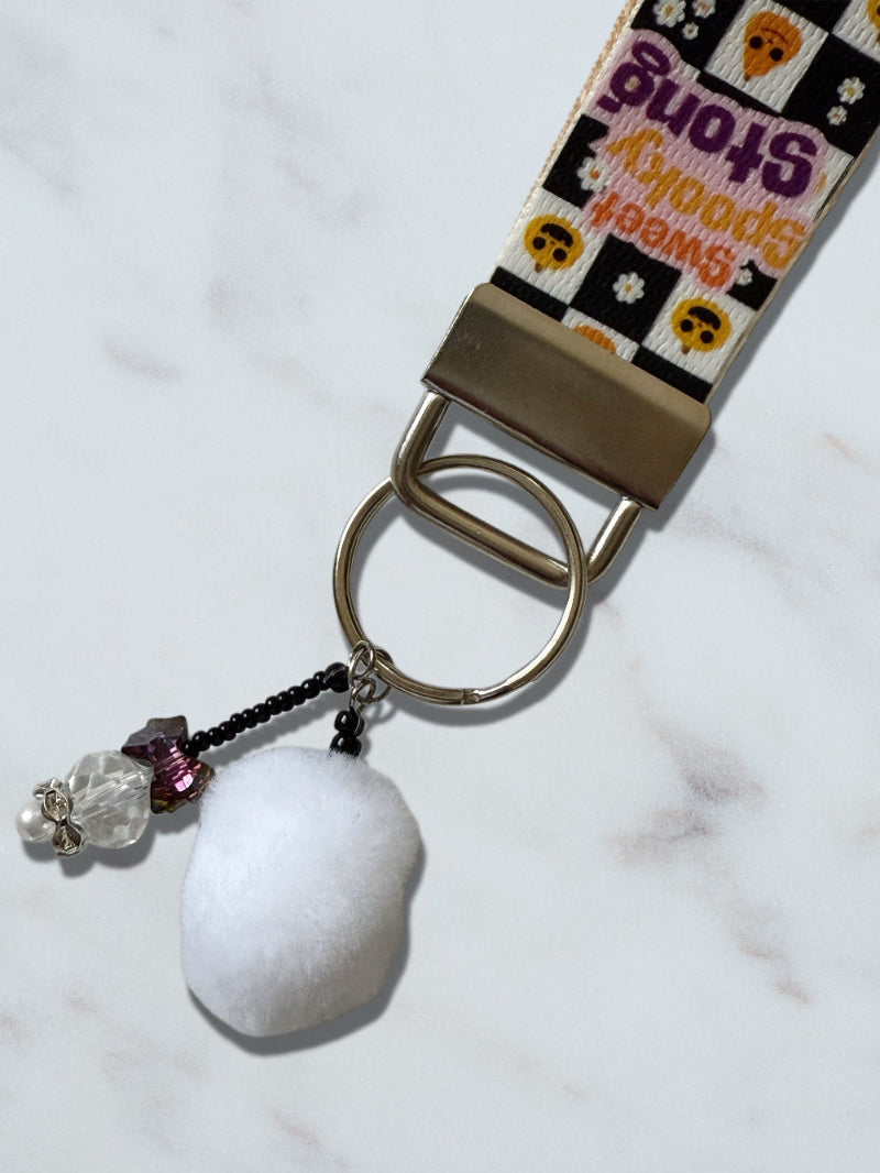 Keychain with decorative strap, key ring, and snowball charm on a white background