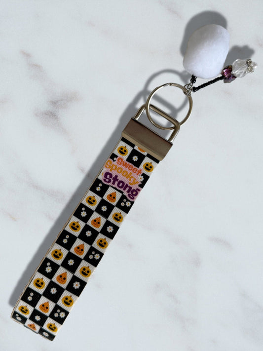 Keychain with checkered pattern and white ball charm on a light background