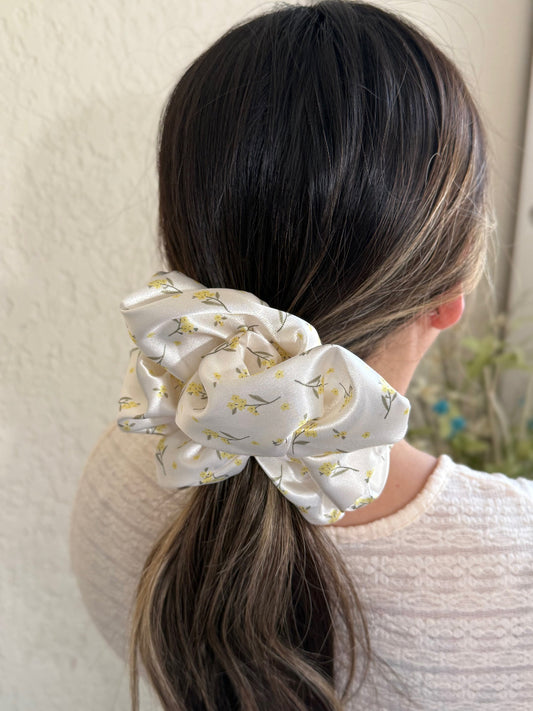 Person with a ponytail wearing a white scrunchie with yellow patterns against a neutral background