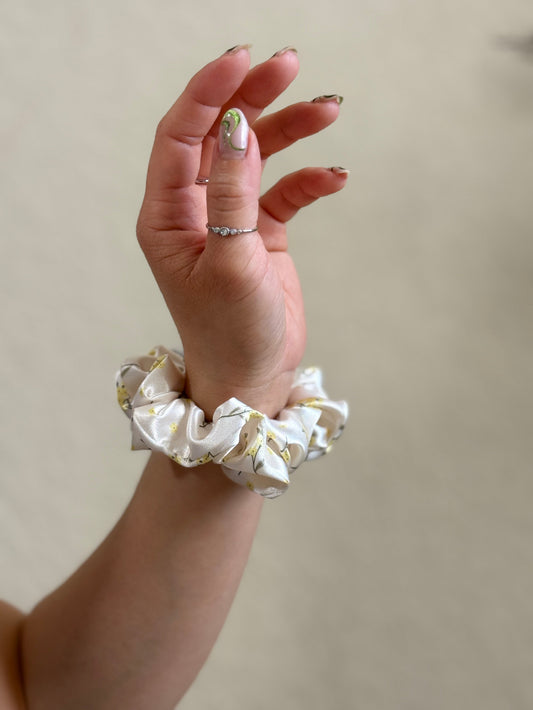 XS satin floral scrunchie in cream with delicate yellow flowers, perfect for thick and long hair, offering a secure and gentle hold.
