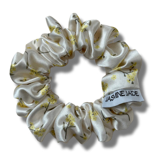 White satin hair scrunchie with yellow floral pattern on a white background