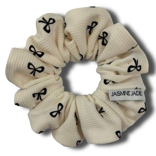 Beige scrunchie with black bow pattern and 'Jasmine Jade' label on a white background