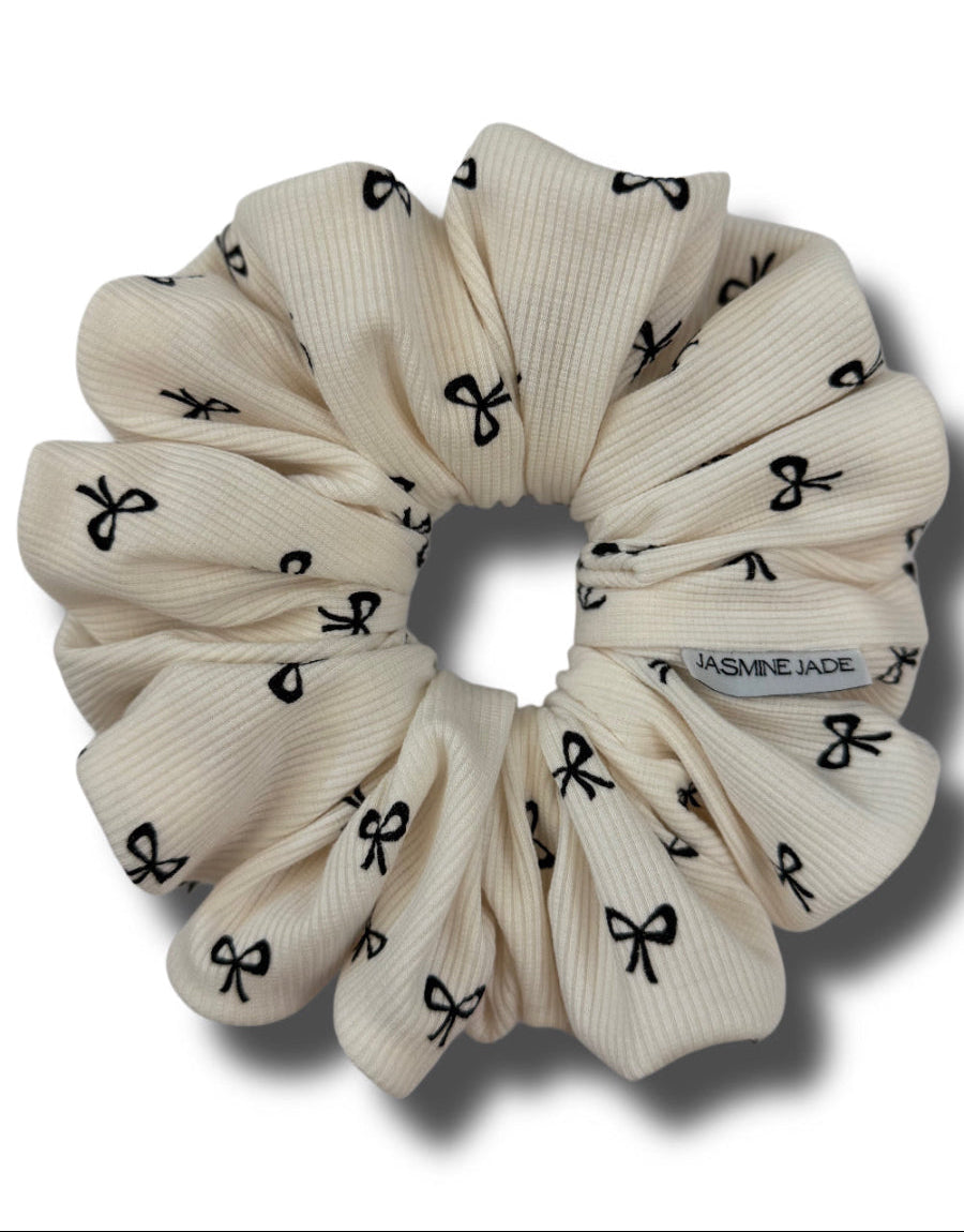 Beige scrunchie with black bow pattern on a white background