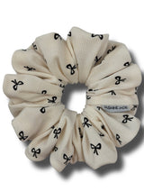 Beige scrunchie with black bow pattern on a white background