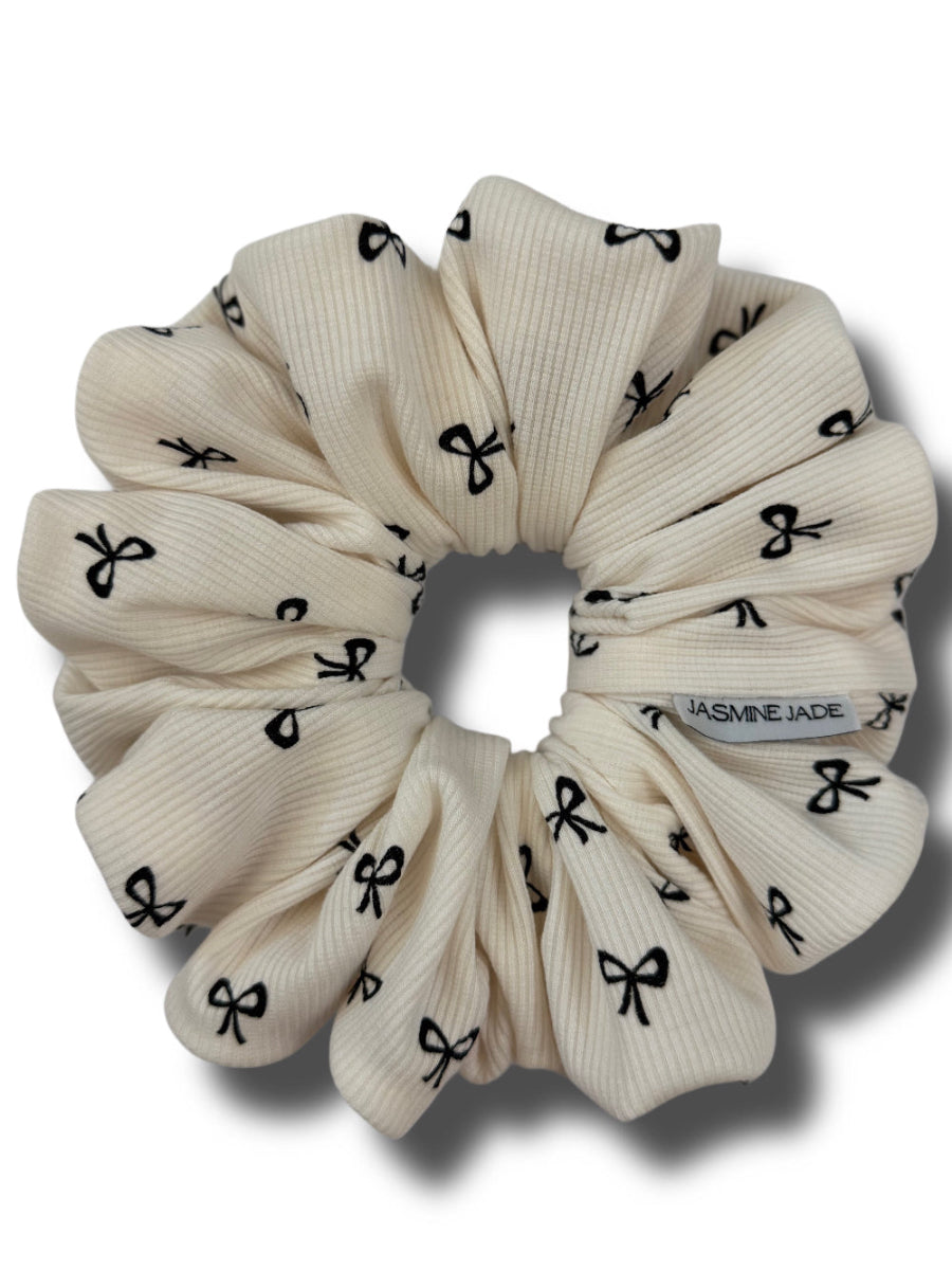Beige scrunchie with black bow pattern on a white background