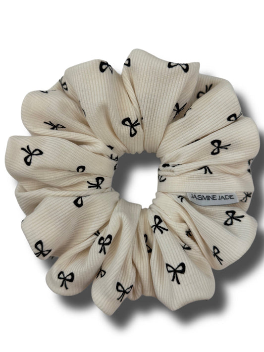 Beige scrunchie with black bow pattern on a white background
