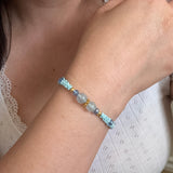 Close-up of a wrist wearing a beaded bracelet with a neutral background