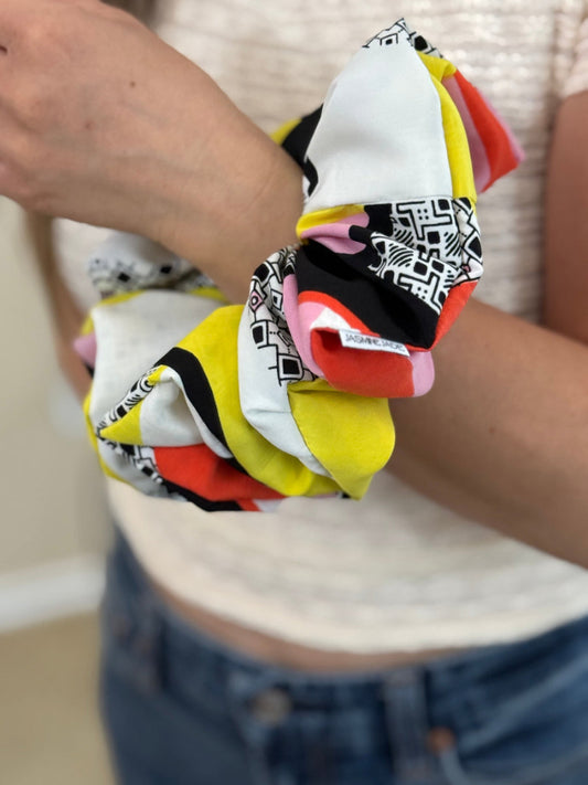 Colorful scrunchie with geometric patterns held by a person.