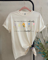 Beige t-shirt with floral designs and text on a plain background