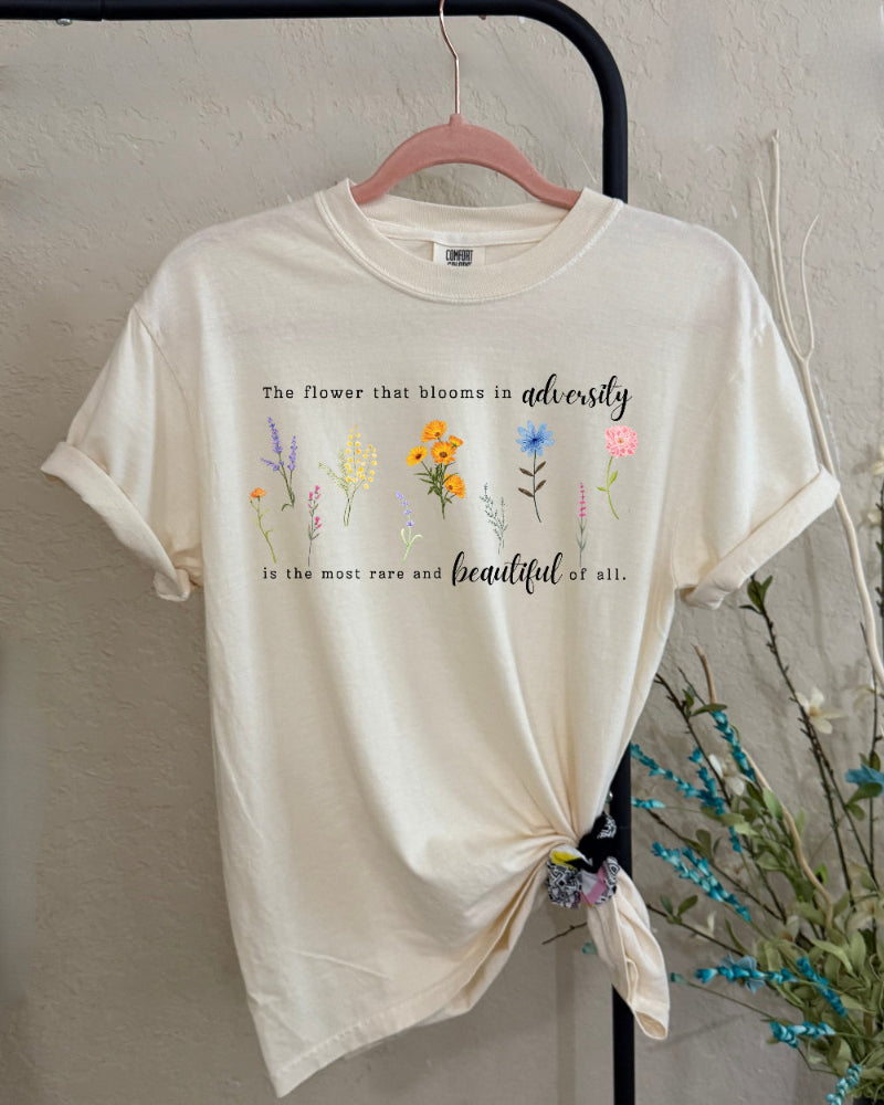 Beige t-shirt with floral designs and text on a plain background