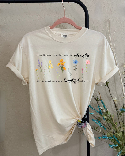 Beige t-shirt with floral designs and text on a plain background