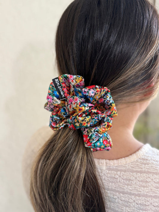 model wearing the Wildflower satin floral scrunchie with a bold multicolor floral print, designed for thick and long hair, offering a secure and stylish hold.