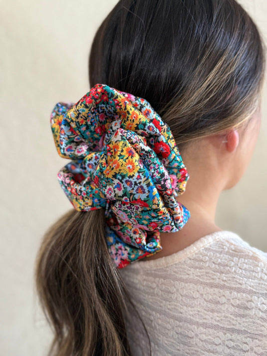 Multicolored floral scrunchie on a ponytail against a neutral background