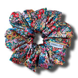 Colorful floral scrunchie with 'Jasmine Jade' label on a white background