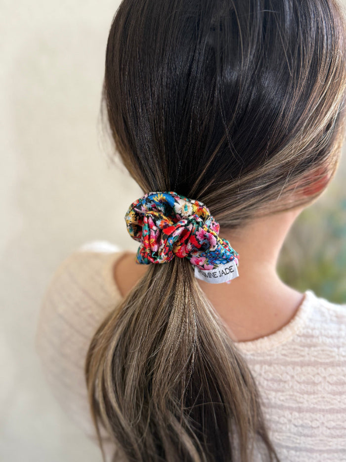 Scrunchie in a ponytail with a visible brand label against a neutral background