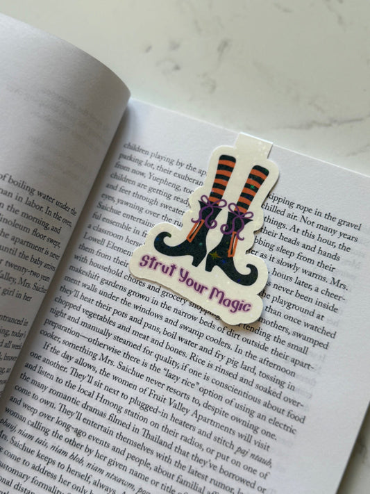 Book with a 'Strut Your Magic' bookmark featuring witch shoes on an open book.