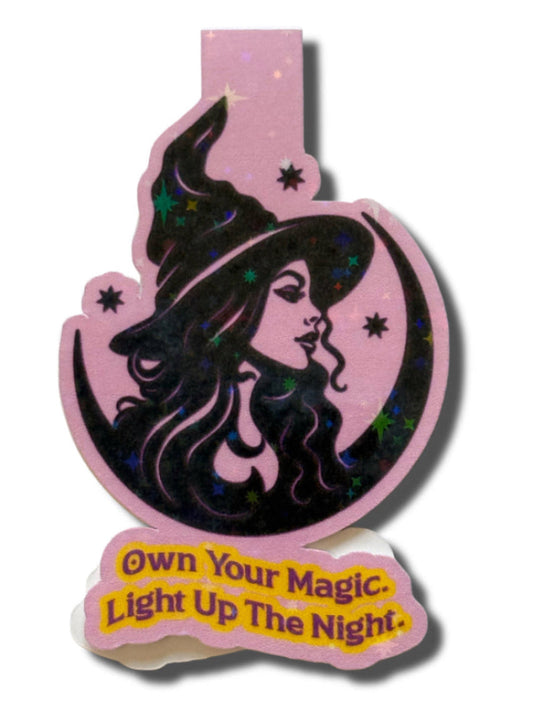 Decorative light with witch design and 'Own Your Magic. Light Up The Night.' text on a pink background