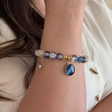 Close-up of a wrist wearing a bracelet with blue and clear gemstones.